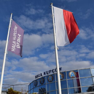 Budynek Hali Kupców Perła we Wrocławiu z widocznymi flagami polskimi przed głównym wejściem od strony al. Armii Krajowej.