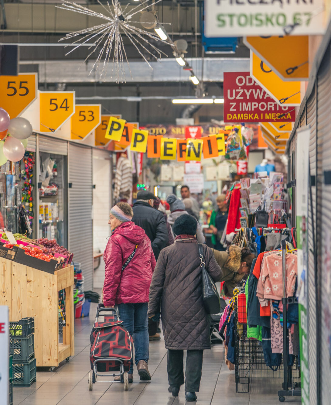 Zakupy w Hali Kupców Perła we Wrocławiu – klienci odwiedzający stoiska z odzieżą, chemią i produktami spożywczymi.